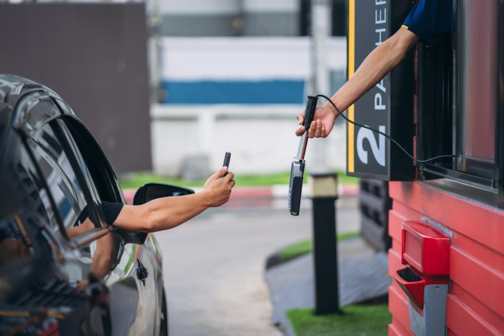 Young Man Pay for food or drinks via mobile phone at drive thru counter., Drive thru and take away